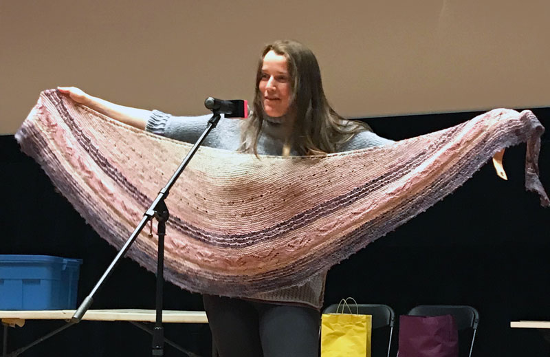 Woman holding colourful knitted shawl.
